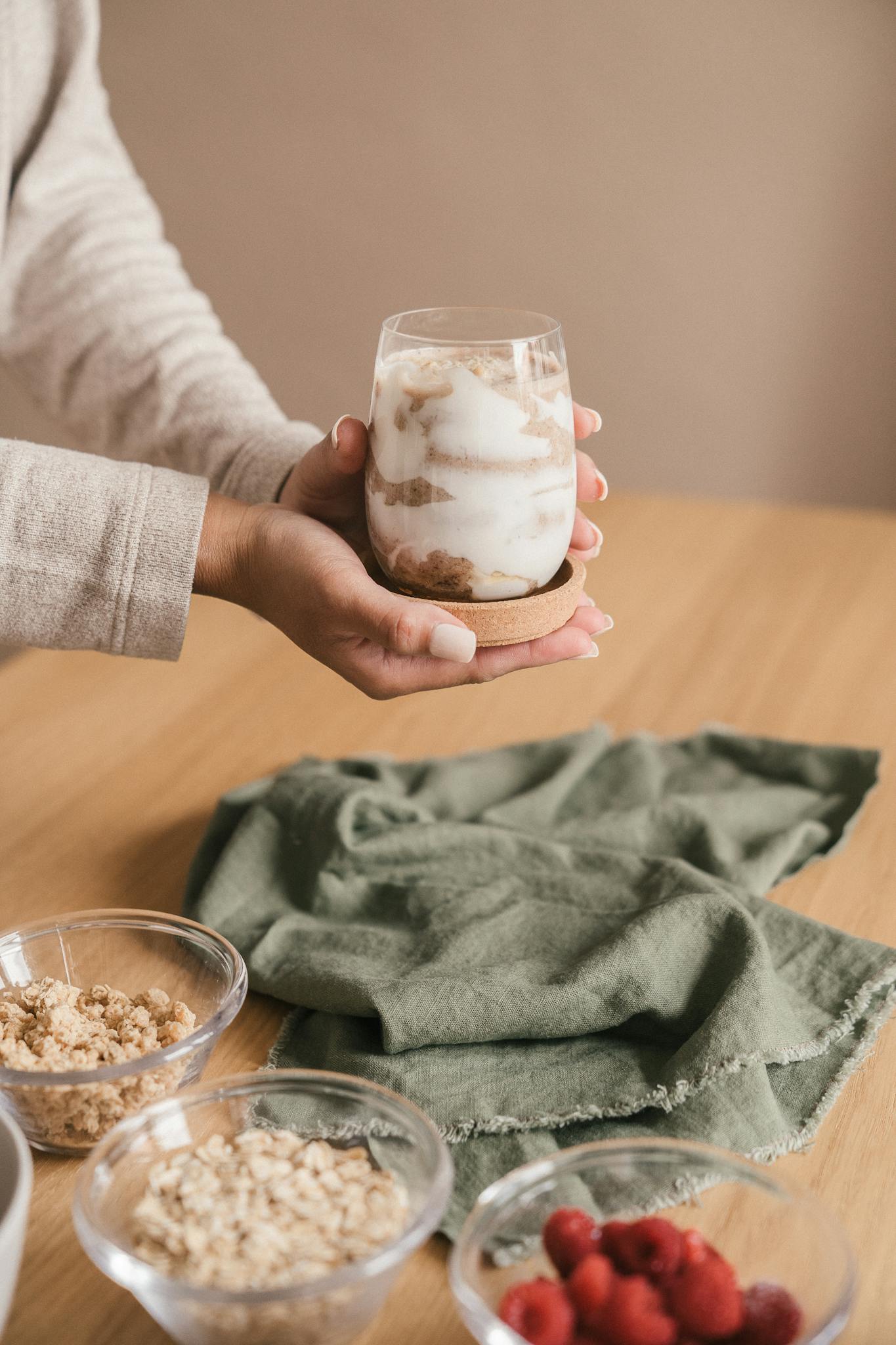 A delicious yogurt parfait with granola and fresh raspberries on a wooden table.