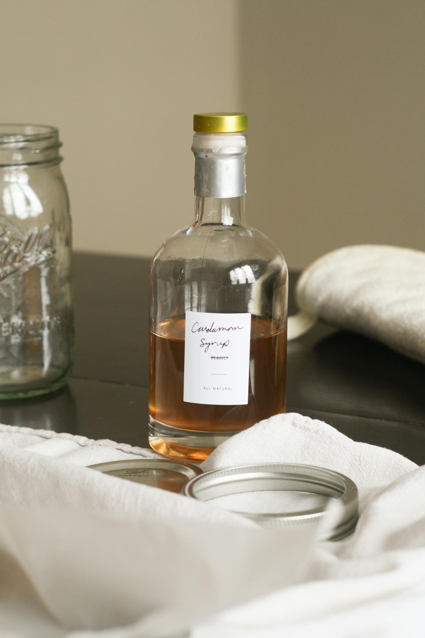 Elegant shot of a cardamom syrup bottle with rustic kitchen elements.