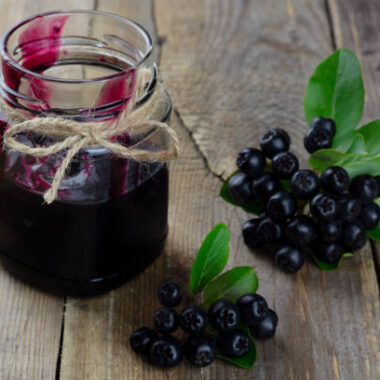 Chokeberry jam and fresh berries on wooden background. horizontal orientation